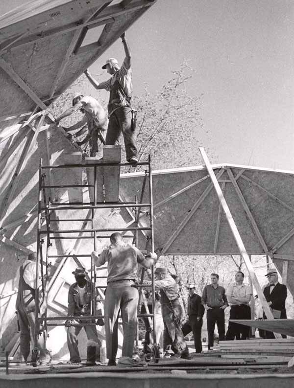 Builder reaching for the skylights building the Bucky Home Dome