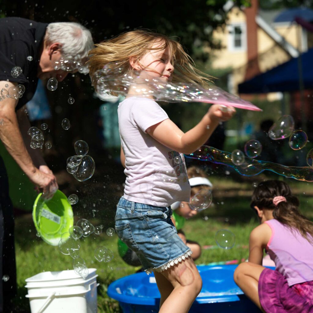 Young visitor creating a giant bubble during an educational activity at the Fuller Dome Home Museum.